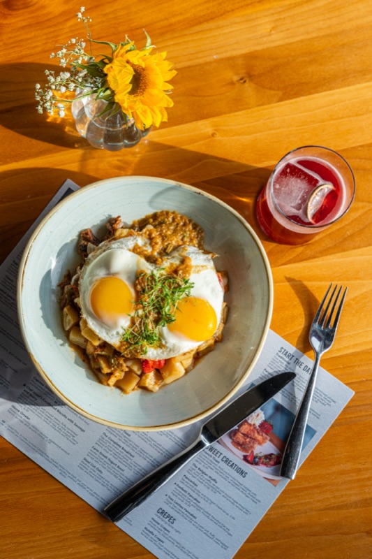 Fried eggs over a breakfast bowl beside sunflowers