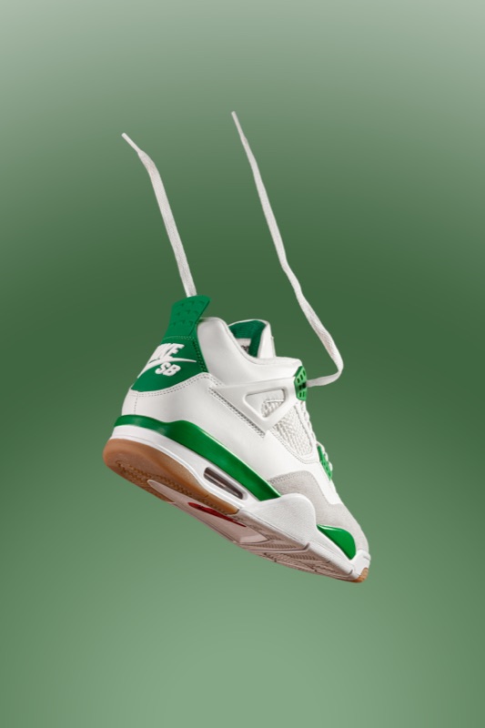 A green and white sneaker hanging by its laces