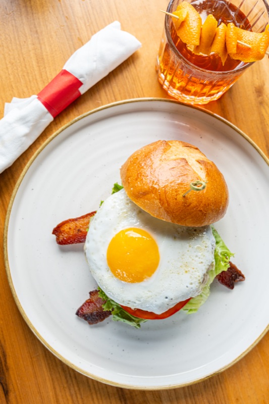 An egg-topped burger with bacon and an old fashioned