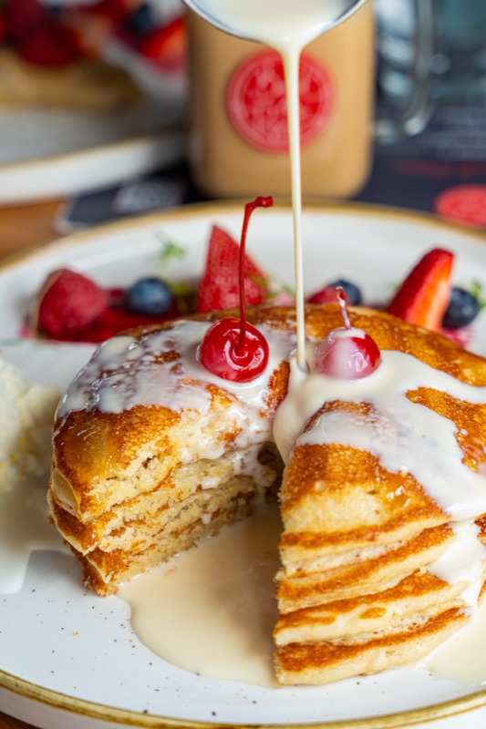 Cream poured over a cut stack of pancakes