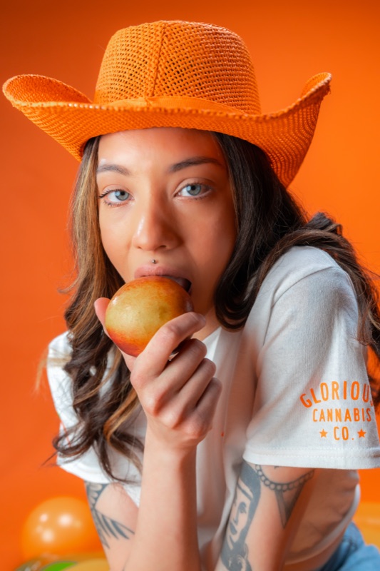 A model in an orange hat biting a peach