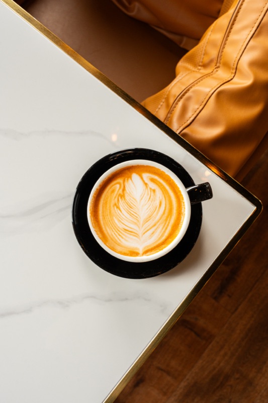 A latte with leaf art on a marble table